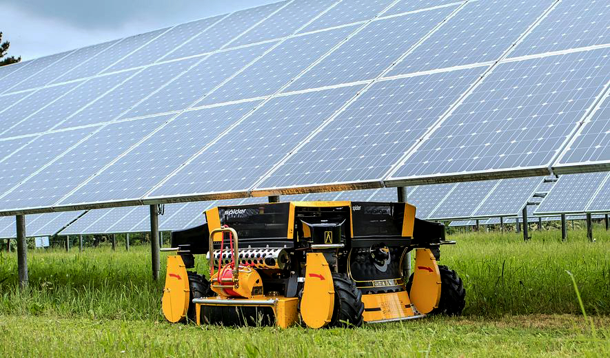 A SPIDER robotic lawn mower maintaining terrain under solar panels.