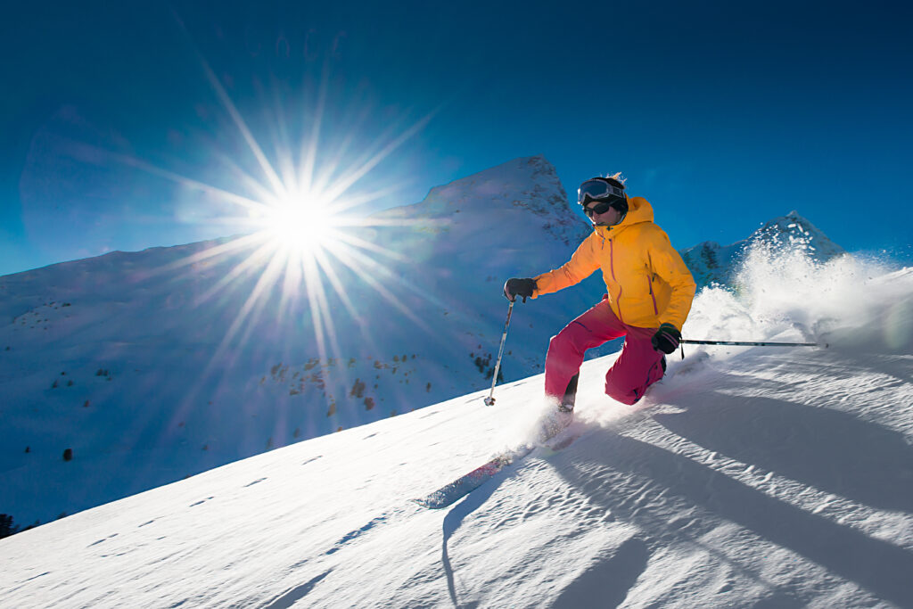 person skiing down steep slope on a sunny day