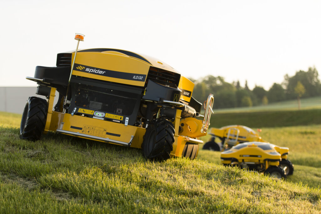 SPIDER ILD02 Positioned on a Hill with Other SPIDER Mowers in the Background at Sunset – Steep Slope Mowers