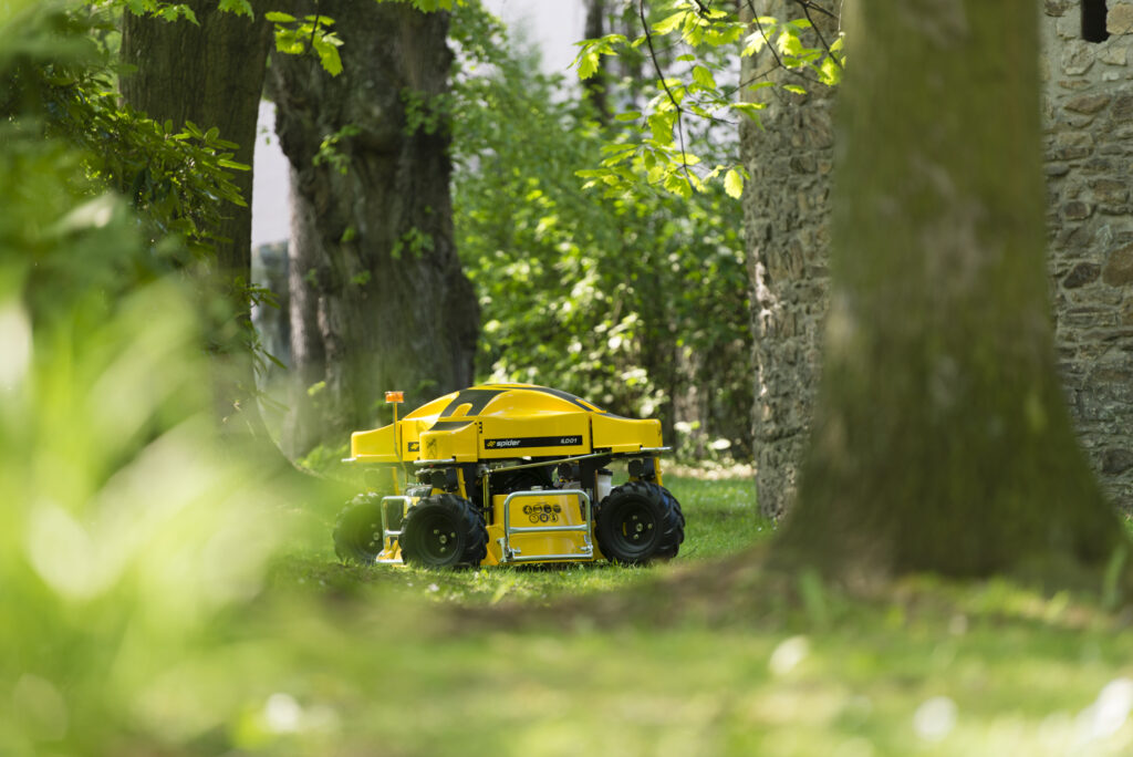 SPIDER ILD01 mower positioned on grass in a wooded area.
