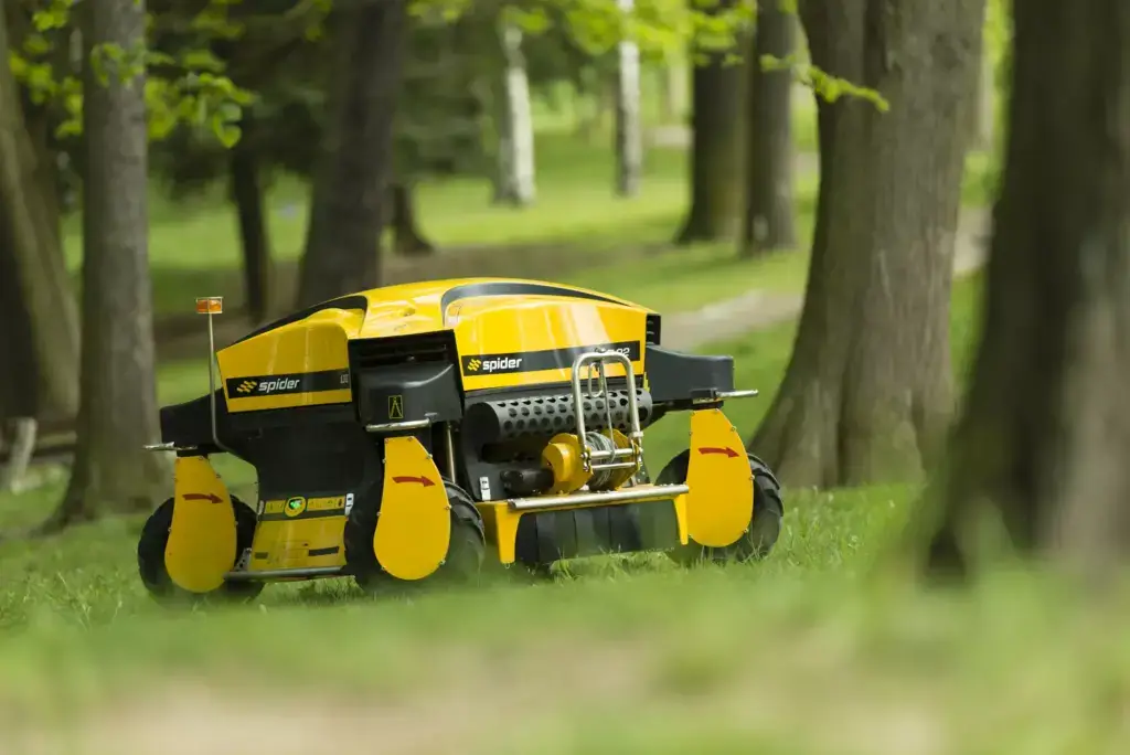 Spider ILD02 Remote Control Slope Mower Stopped on the Grass Surrounded by Trees. 15 years of Spider Mower USA.
